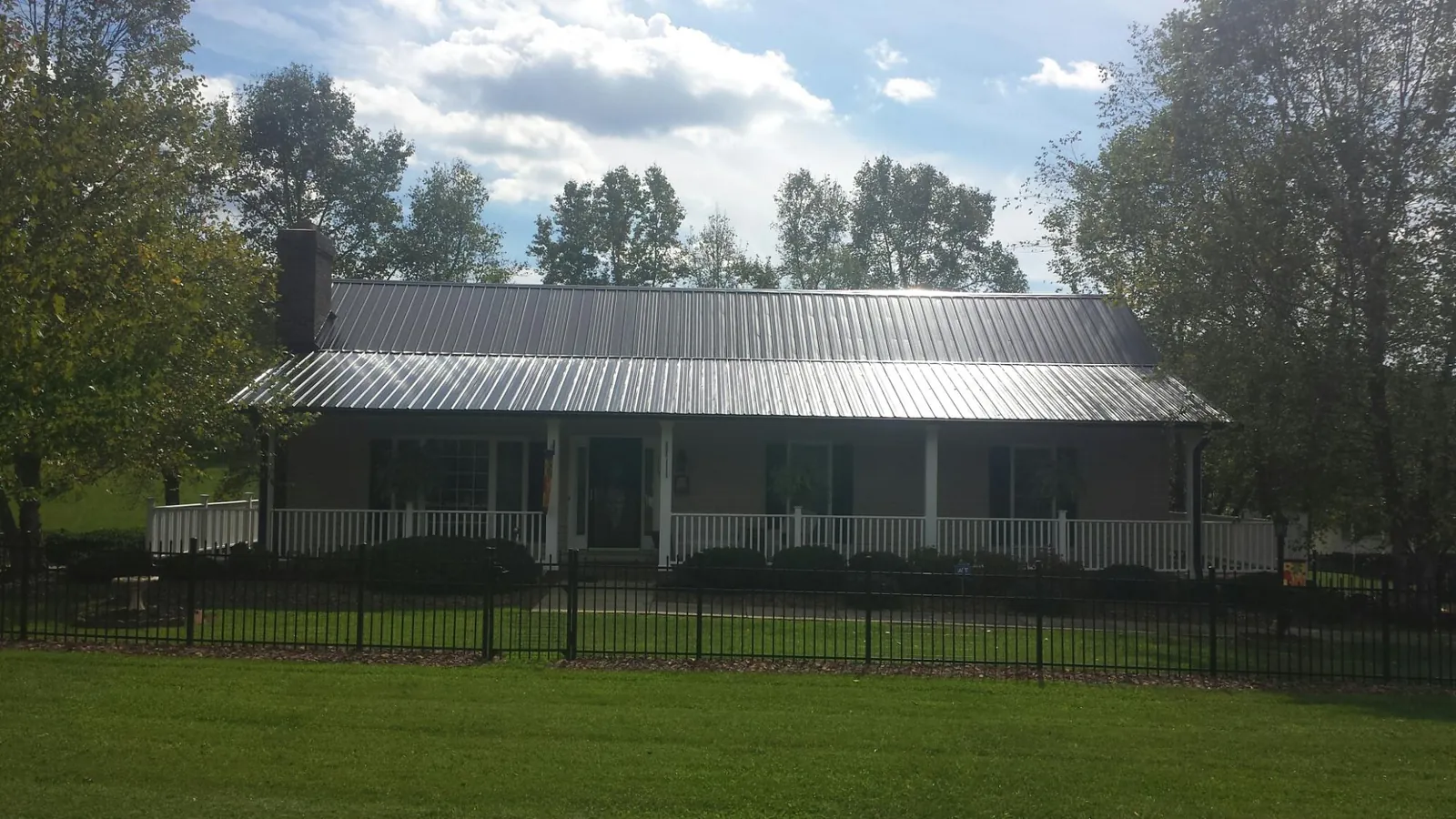 Gray metal roof on a brick ranch with a full width front porch — Gutter Guard Installation work by our crew in Burlington